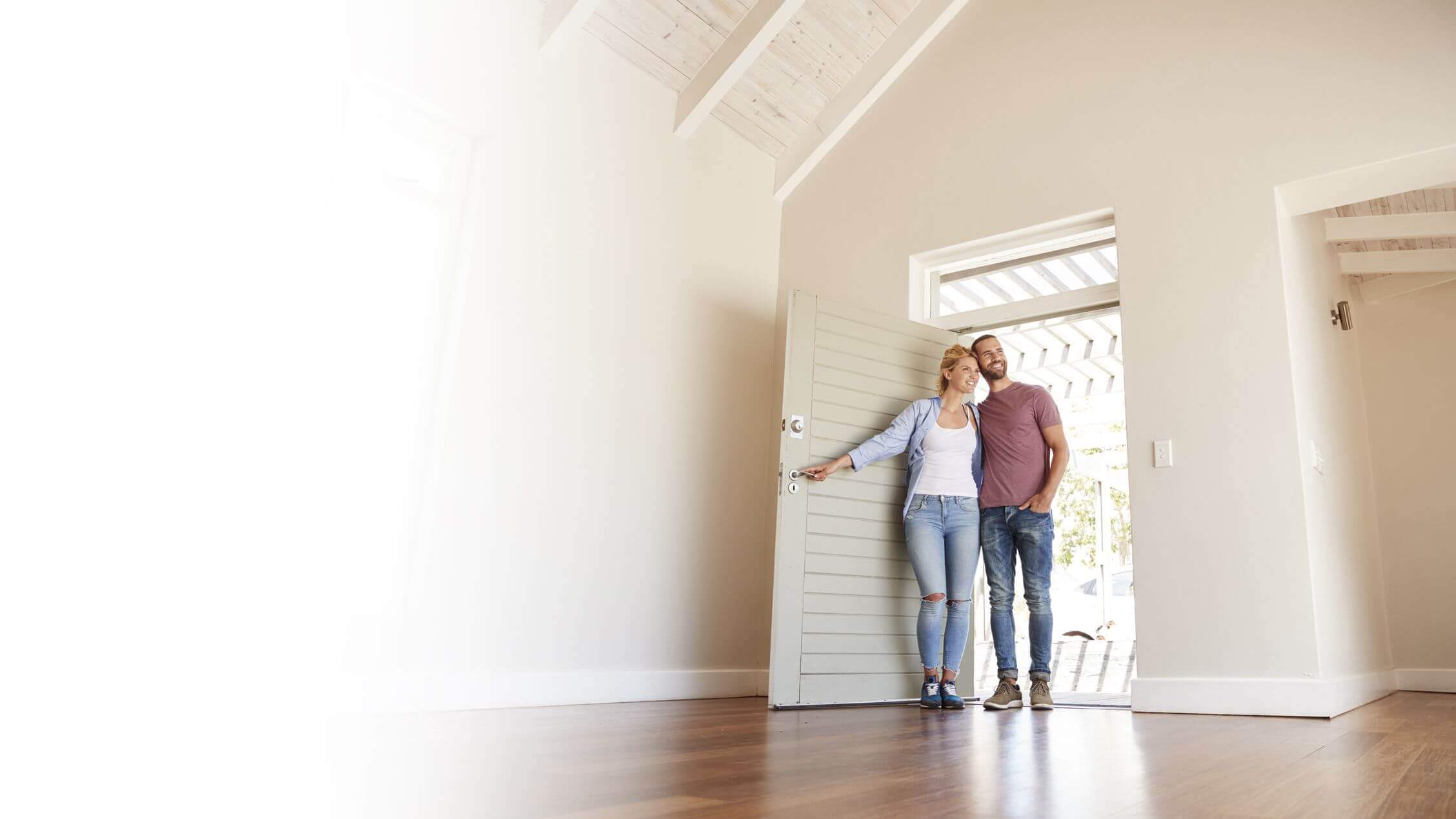 Banner image of couple at entry of home with lady opening the front door and couple smiling and looking inside